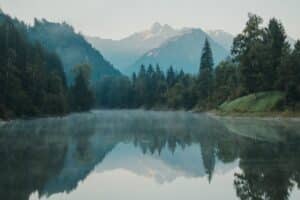 Ruhiger Fluss mit Bergen und Wald im Allgäu als Symbol für innere Ruhe, Klarheit und neue Perspektiven