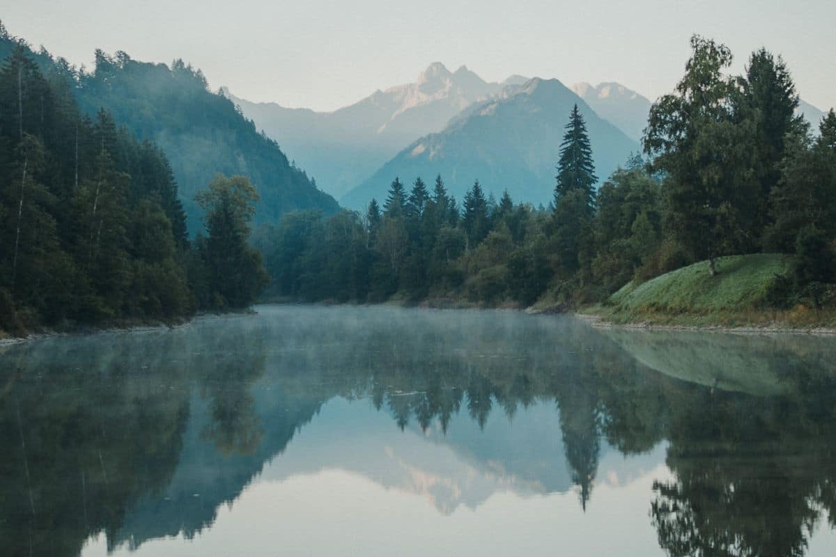 Ruhiger Fluss mit Bergen und Wald im Allgäu als Symbol für innere Ruhe, Klarheit und neue Perspektiven