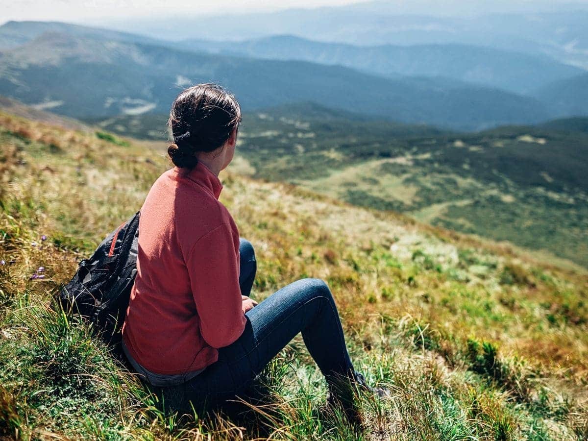 Frau blickt in die Weite der Berge und nimmt sich Zeit für Orientierung und Klarheit.